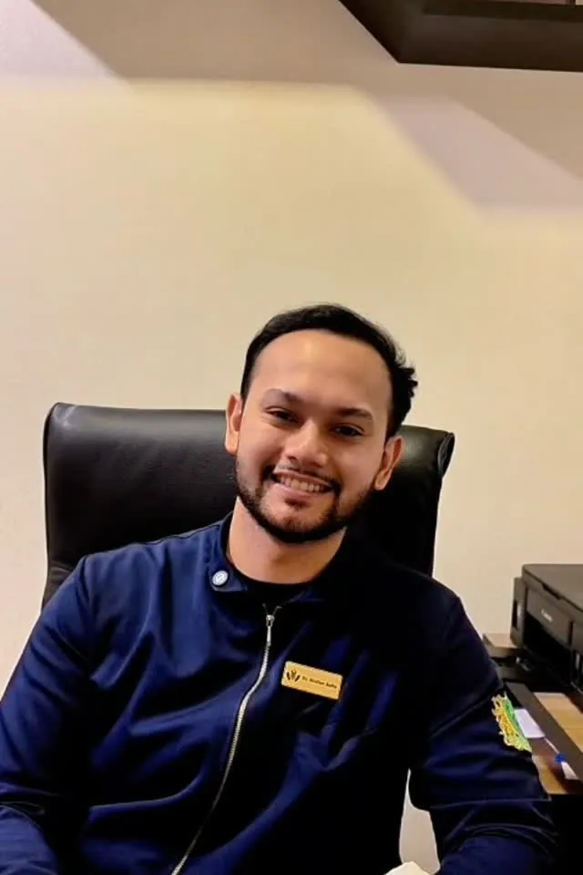 Dr. Giulian Saito, fisioterapeuta, sorrindo no consultório